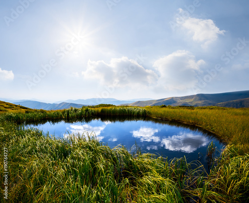 small lake on a mountain plateau under a sparkle sun