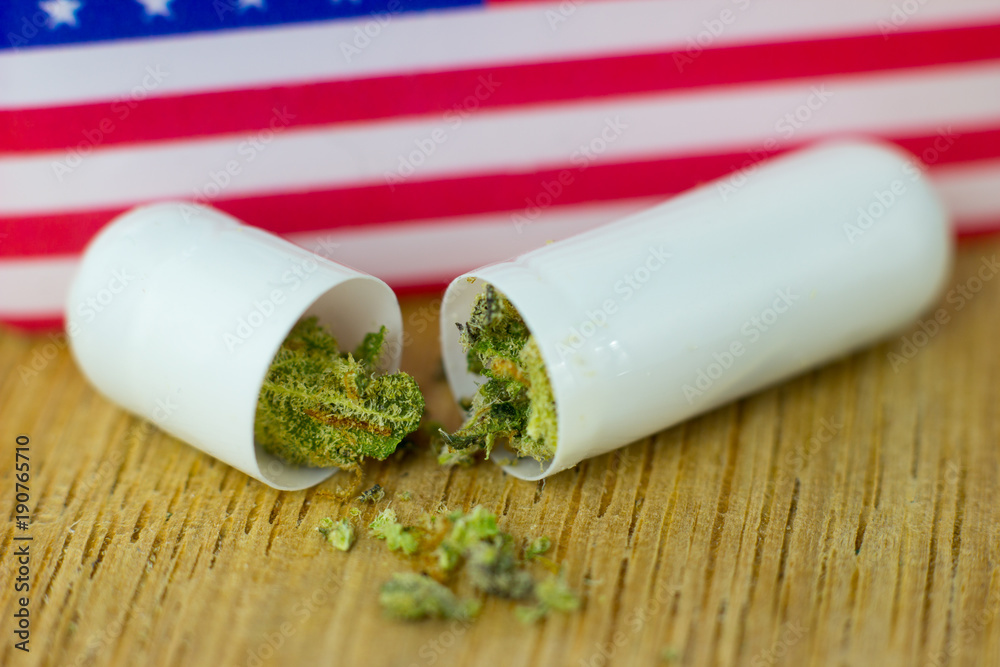 Medical Pills and tablets Cannabis - marijuana oil, resin and flowers with USA flag on fresh oak wood background. Medical Pills and tablets Cannabis - marijuana oil, resin and flowers with USA flag on fresh oak wood background.