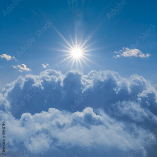 sparkle sun among a dense clouds on a blue sky background