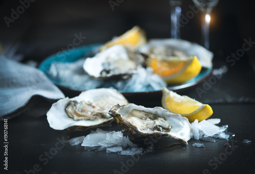 Fresh oysters close-up on blue plate, served table with oysters, lemon and champagne in restaurant. Gourmet food