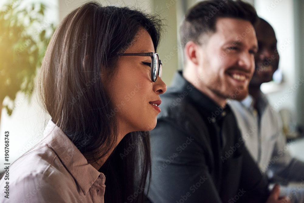 Smiling diverse businesspeople sitting together during an office meeting Smiling diverse businesspeople sitting together during an office meeting