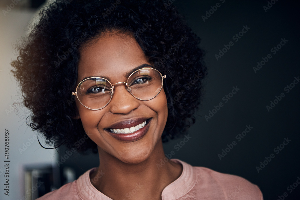 Smiling young African businesswoman standing in an office Smiling young African businesswoman standing in an office
