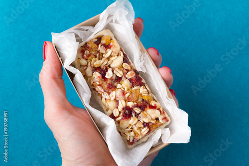 a female hand holds useful sweetness from nuts, oatmeal, honey, red berries, chocolate, raisins, dried apricots