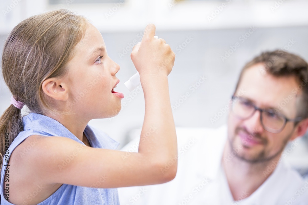 Girl using inhaler with doctor watching Girl using inhaler with doctor watching