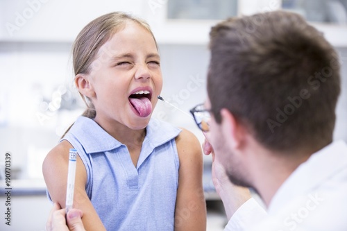 Doctor taking a swab from a girl's mouth