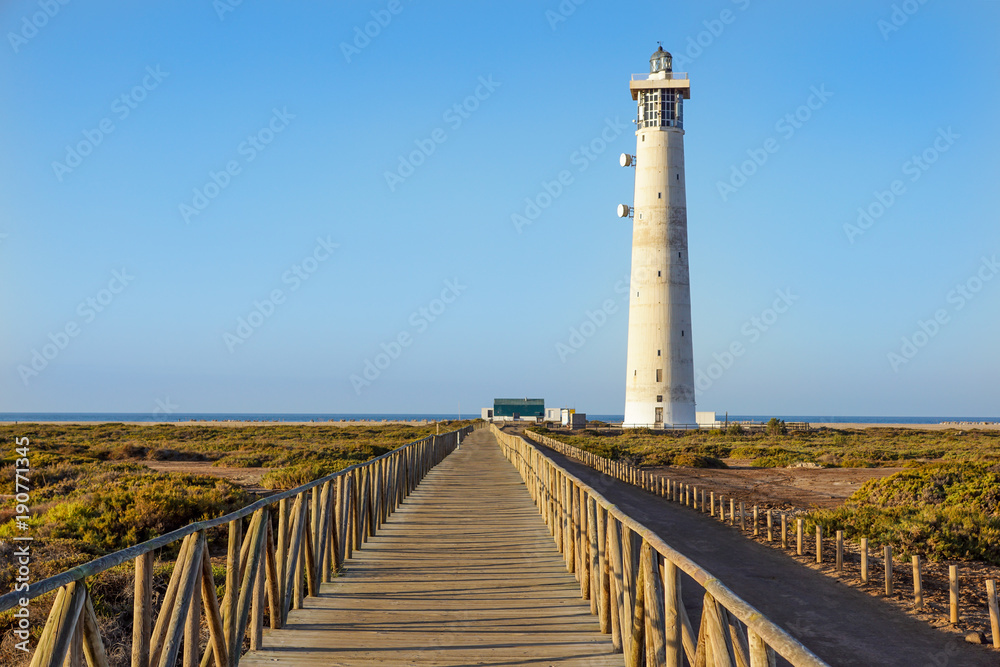 Wooden footbridge walkway to beach near Morro Jable lighthouse in warm sunset light, Fuerteventura island, Spain