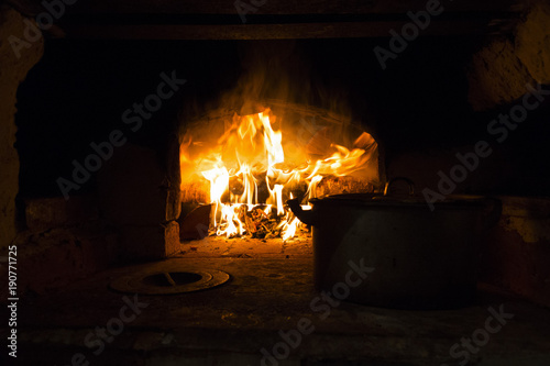 Pan and a fire in the village stove. Russia.