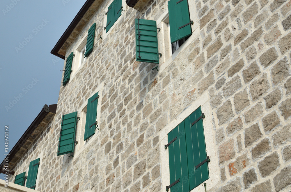 Open and closed wooden shutters on a house facade made of stone Open and closed wooden shutters on a house facade made of stone