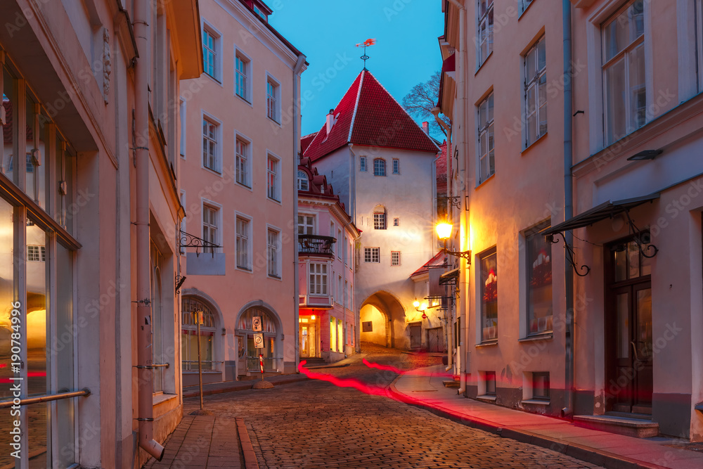 Naklejka premium Beautiful illuminated medieval street in Old Town of Tallinn during evening blue hour, Estonia
