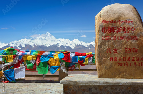 Everest from the famous view point with the monument stone on the last pass at the road to Everest base camp. Buddhist prayer flags around, Himalaya range, Tibet, China, Asia. photo