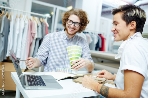 Young creative colleagues searching in the net while discussing and choosing new colors