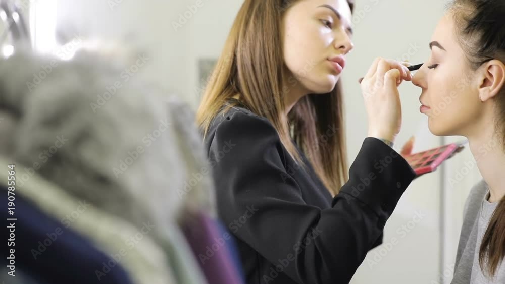 Visagist doing make up using brush for model girl in salon Visagist doing make up using brush for model girl in salon