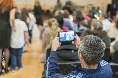 Dad takes pictures of children in the garden who perform on stage in front of their parents