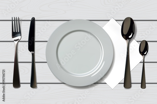 Empty realistic plate with spoon, knife and fork on a wooden background. Cutlery on a wood table