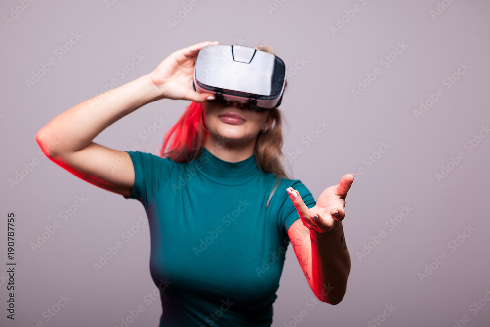 Sexy woman wearing VR virtual reality head set on gray background Sexy woman wearing VR virtual reality head set on gray background