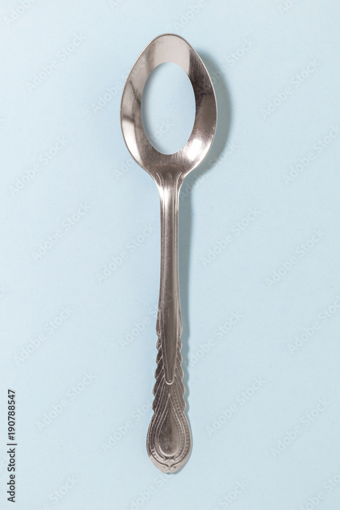 Holey spoon isolated on blue background. Dieting and food intake control. Holey spoon isolated on blue background. Dieting and food intake control.