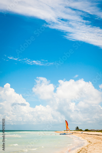 Tropical beach with bright sail boat on shore