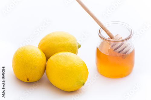 Honey and fresh lemon over white background.