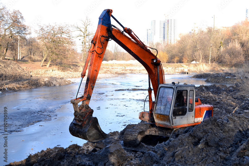 Excavation in the park. Excavator working on the lake. Excavation in the park. Excavator working on the lake.