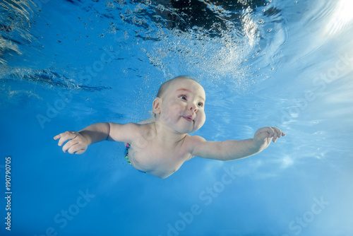 little boy learns to swim underwater in the pool photo