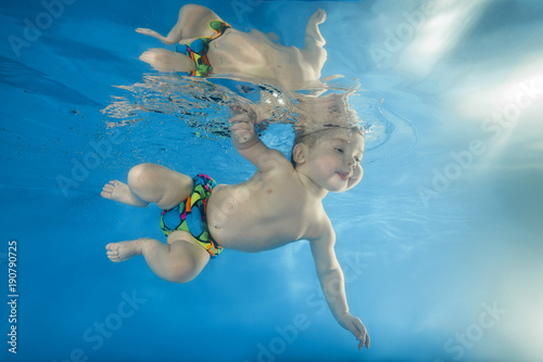 little boy learns to swim underwater in the pool
