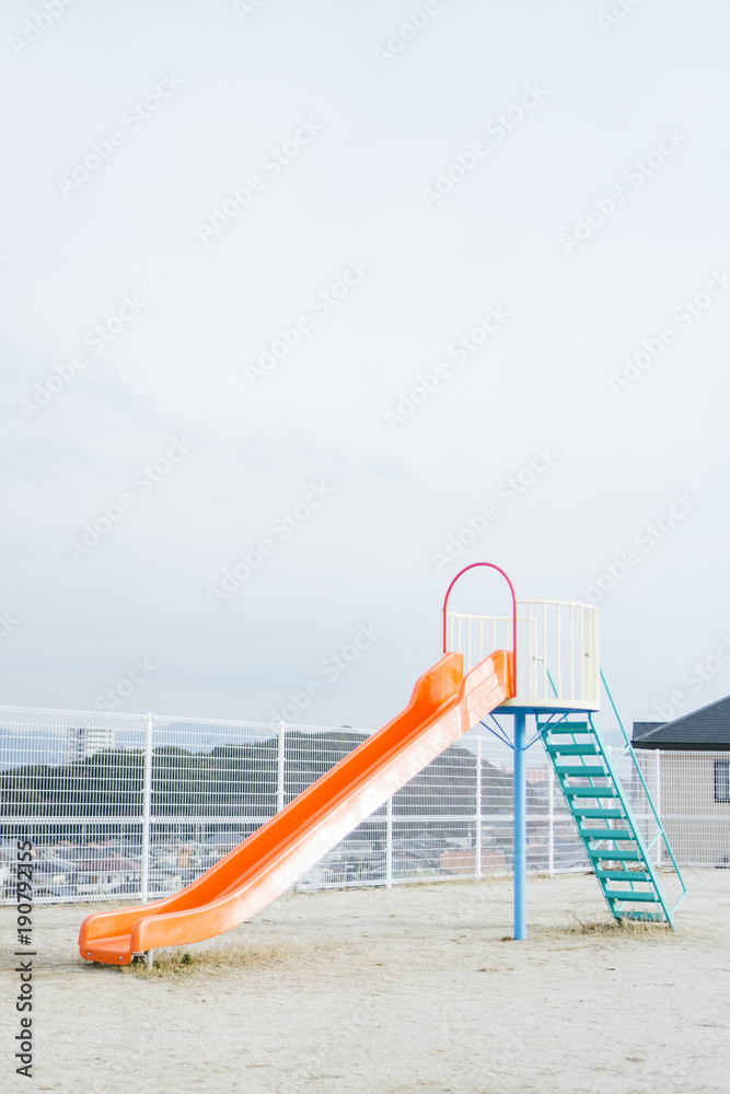 Naklejka premium A slide in the playground with nobody on it while the weather is cloudy.