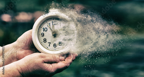 Foto Vintage alarm clock dissolving in hand, time running out concept