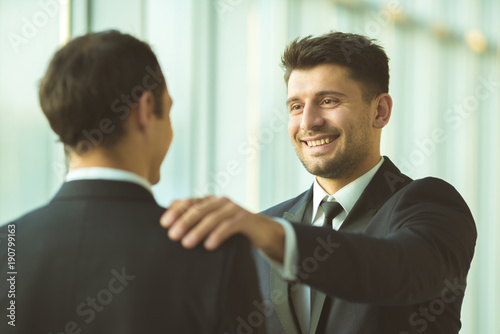 The happy men pat on the shoulder in the office