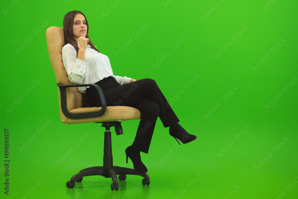 The woman sitting on the chair on the green background The woman sitting on the chair on the green background