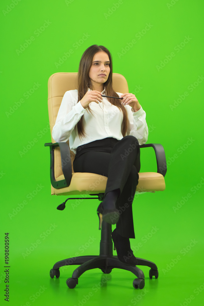 The businesswoman sitting on the green background The businesswoman sitting on the green background