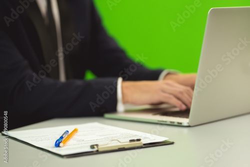 The man works with the laptop on the green background