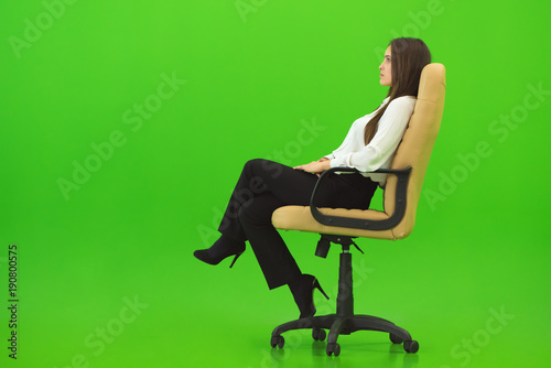 The woman sitting on the chair on the green background © realstock1