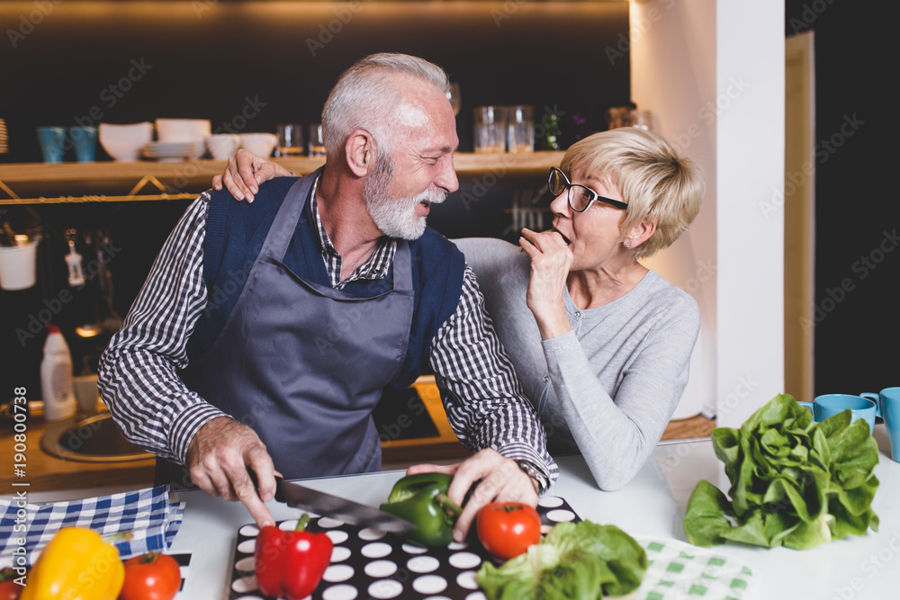 Senior couple preparing lunch together in kitchen.