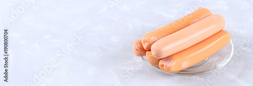 Raw sausages on a wooden board on a gray concrete table. Banner. photo