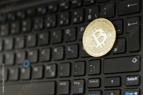 Shiny bitcoin on laptop keyboard photo