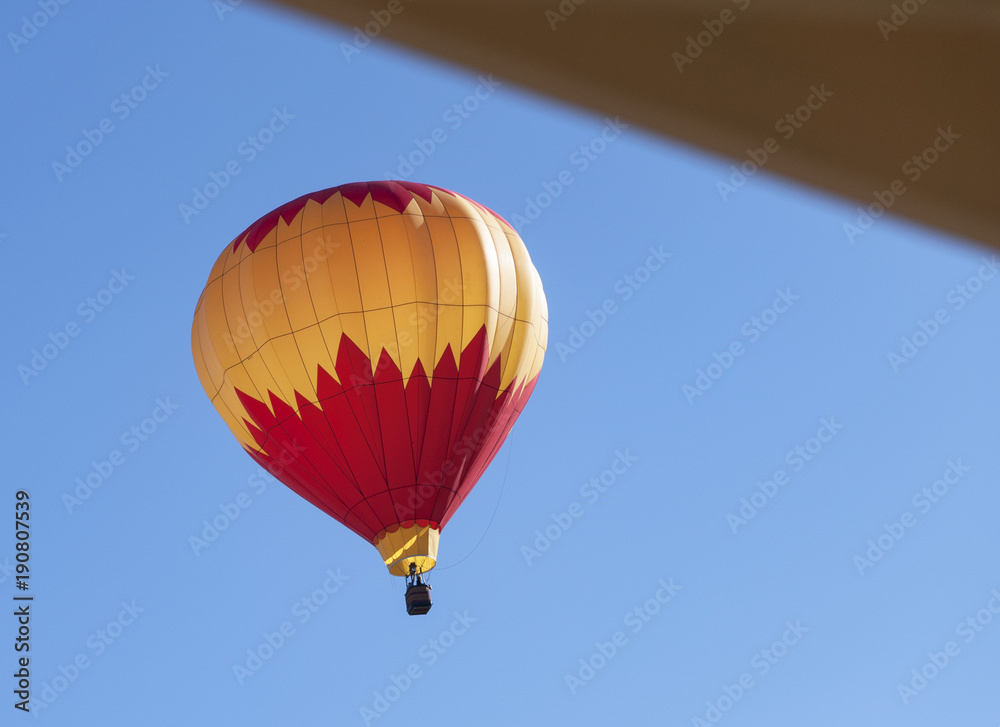 Fototapeta premium colorful hot air balloon descending near a house