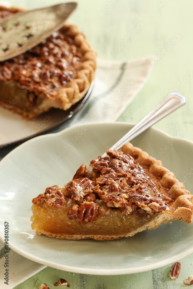 Close up of homemade Classic Pecan pie and a a slice on plate, selective focus