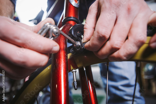 Theme repair bikes. Close-up of a Caucasian man's hand use a hand tool hexagon set to adjust and install Rim Brakes on a red bicycle