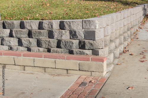 Residential retaining wall featuring a variety of stacked blocks and mortared brick textures, horizontal aspect