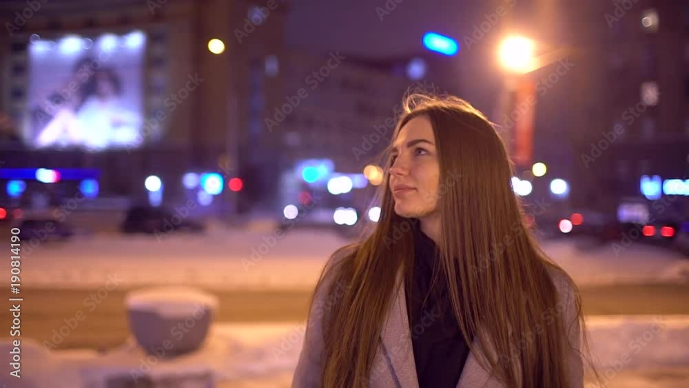 Portrait of young Beautiful woman in the city by the street. Young Beautiful Women Walking At Night In City Smiling And Looking In Camera Traffic In Background. SLOW MOTION Portrait of young Beautiful woman in the city by the street. Young Beautiful Women Walking At Night In City Smiling And Looking In Camera Traffic In Background. SLOW MOTION