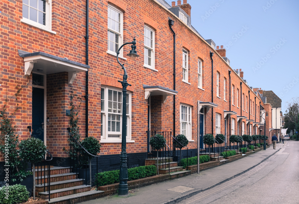 Red brick modern architecture terrace houses ( row houses ) with a retro, vintage Victorian sytle. There a vold fashin style street lamps , sash window and steps with railings leading to the front doo