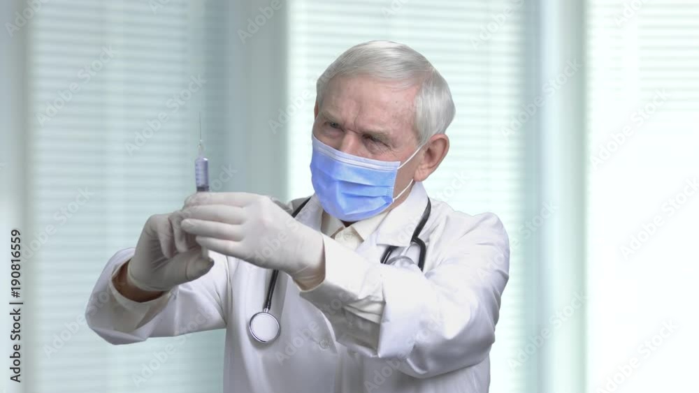 Gloomy old doctor with syringe. Anesthetist with syringe in jalousie background. Gloomy old doctor with syringe. Anesthetist with syringe in jalousie background.