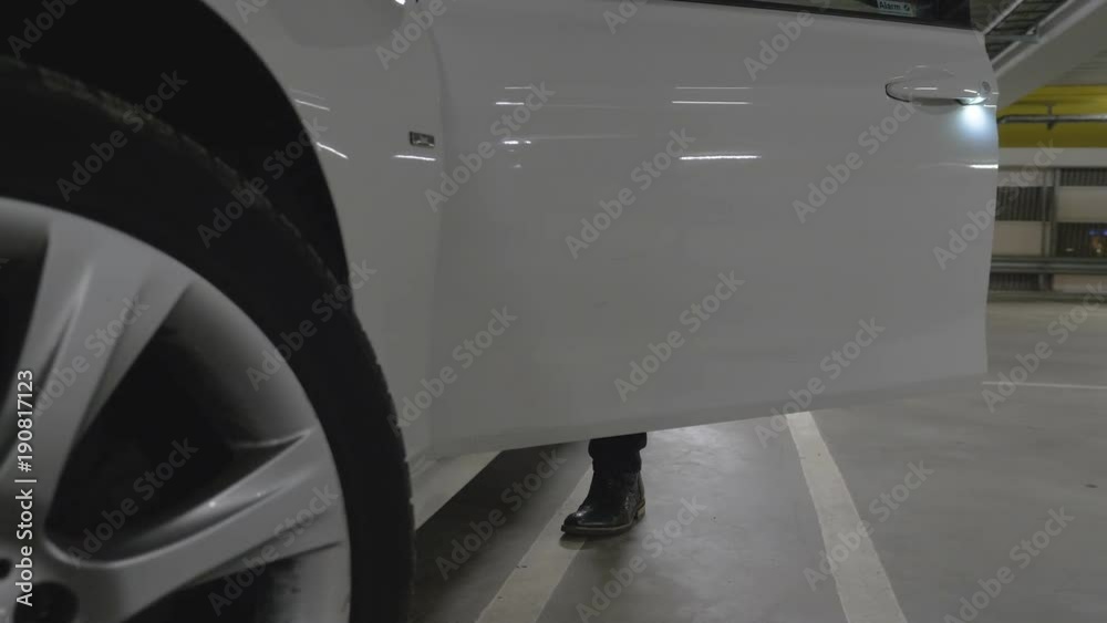 man gets in to a car parked in a garage