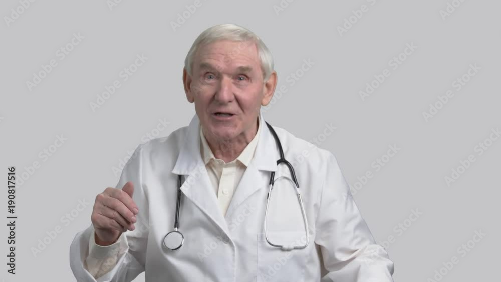 Old pediatrician cheer up kids. Granddad in white coat and stethoscope telling funny stories, grey isolated background. Old pediatrician cheer up kids. Granddad in white coat and stethoscope telling funny stories, grey isolated background.