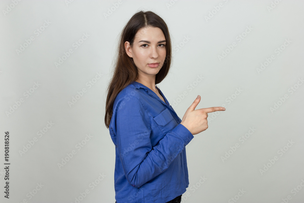 Portrait of a pretty serious woman points and looks to the camera over gray background Portrait of a pretty serious woman points and looks to the camera over gray background
