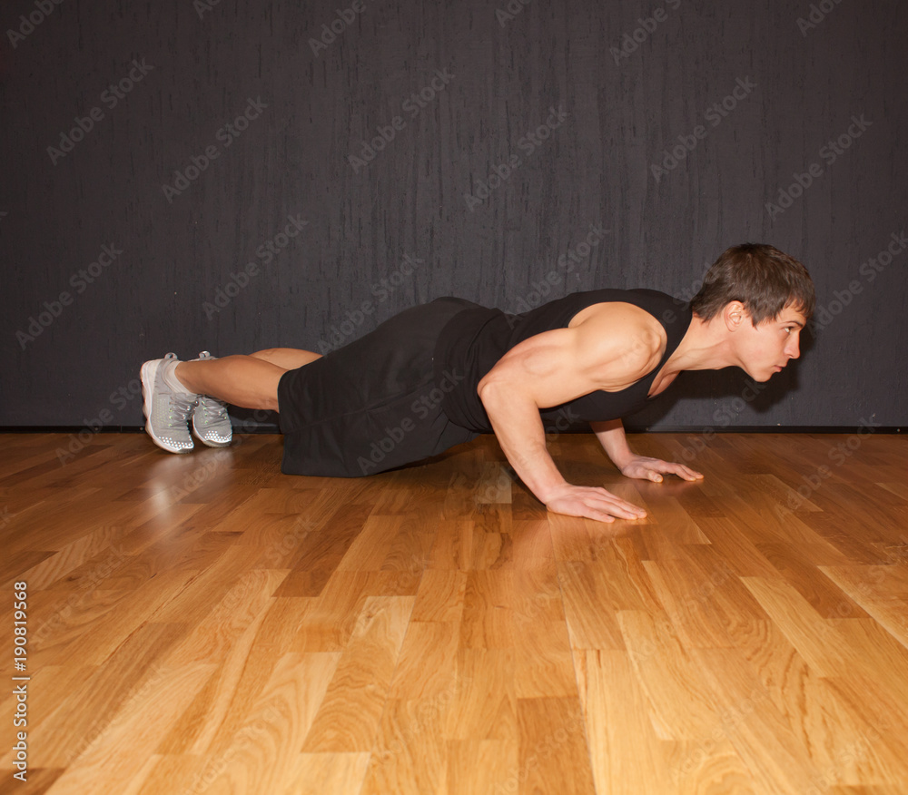 muscular sportsman doing exercise push ups in gym interior