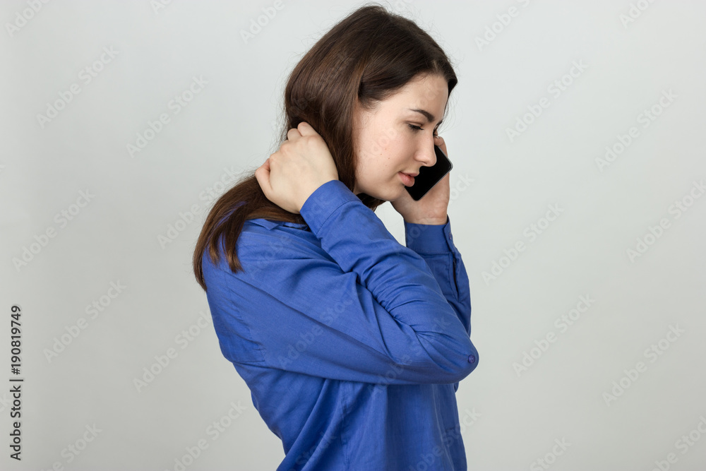 Portrait of a pretty woman holding her neck in pain and discomfort calling a doctor Portrait of a pretty woman holding her neck in pain and discomfort calling a doctor