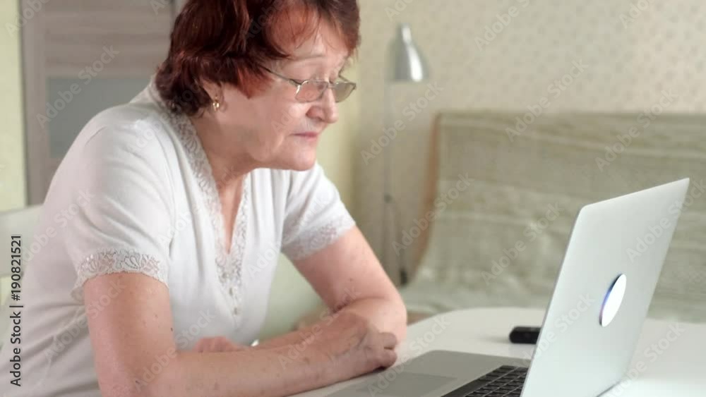 old woman talk with her granddaughter on skype using a laptop