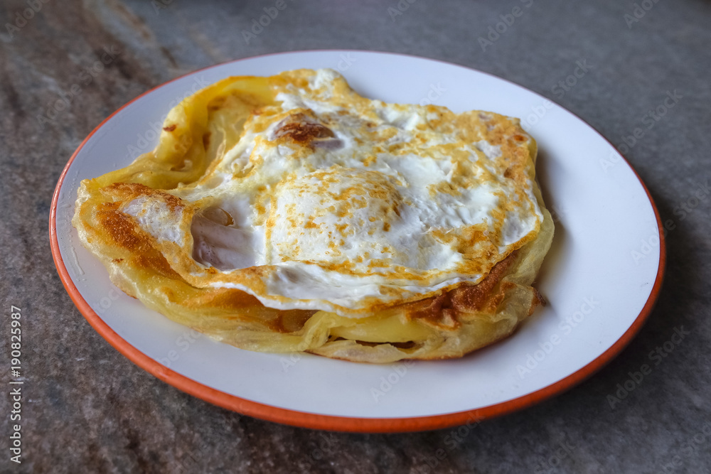 Roti canai with egg  on the plate over dining table