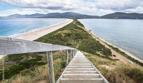Looking down a staircase at a very narrow isthmus with a road along it on Bruny Island, Tasmania.